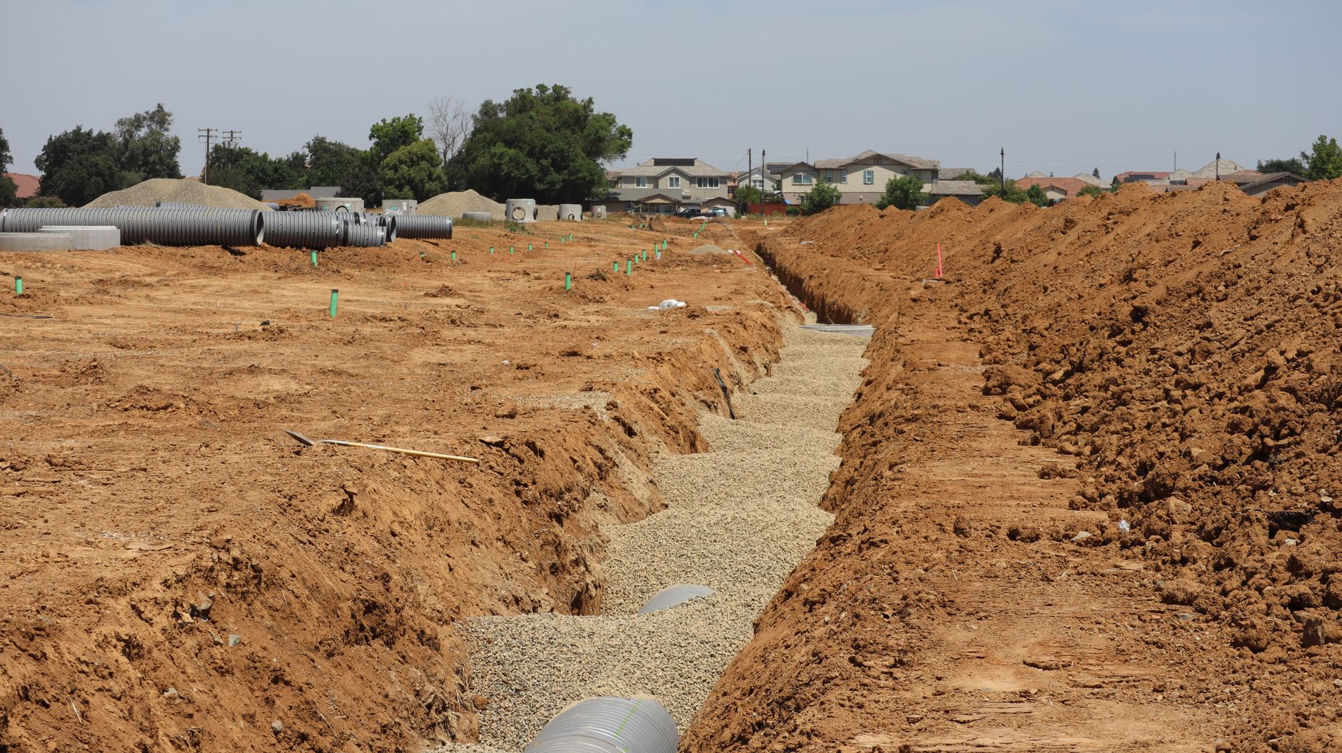A long drainage trench running across a subdivision